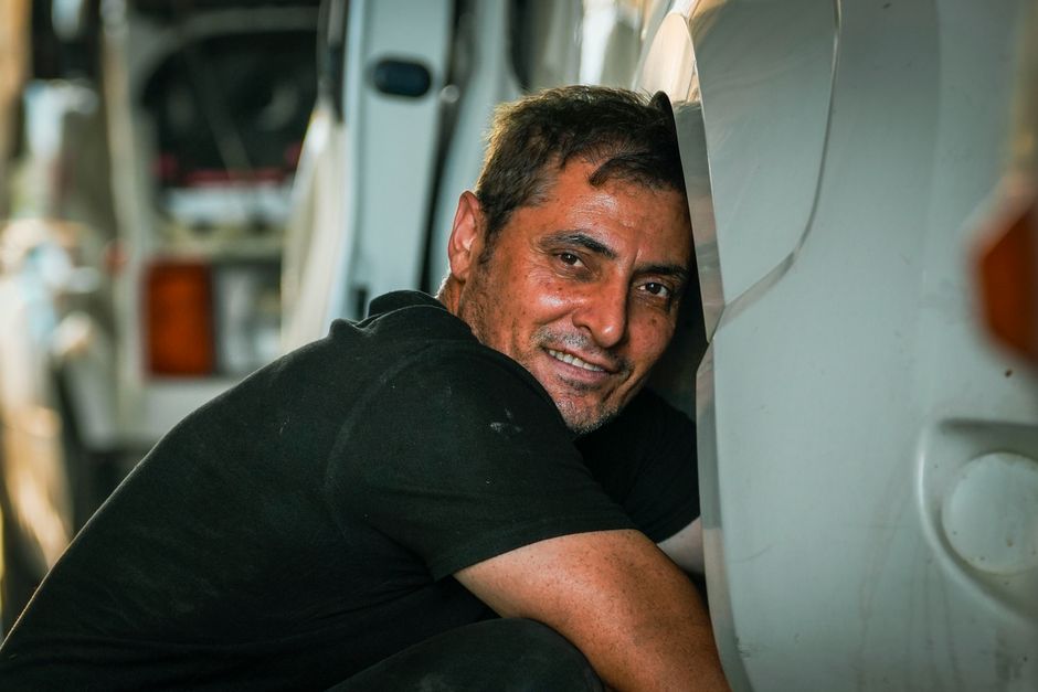 Friendly and professional auto glass mechanic smiling next to a vehicle